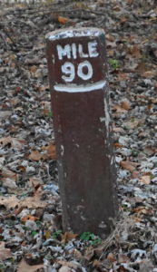 A leaning mile marker post.
