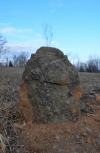 A upright stone set in the ground as a grave marker.